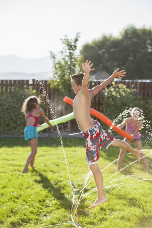 Caucasian children playing in the sprinkler