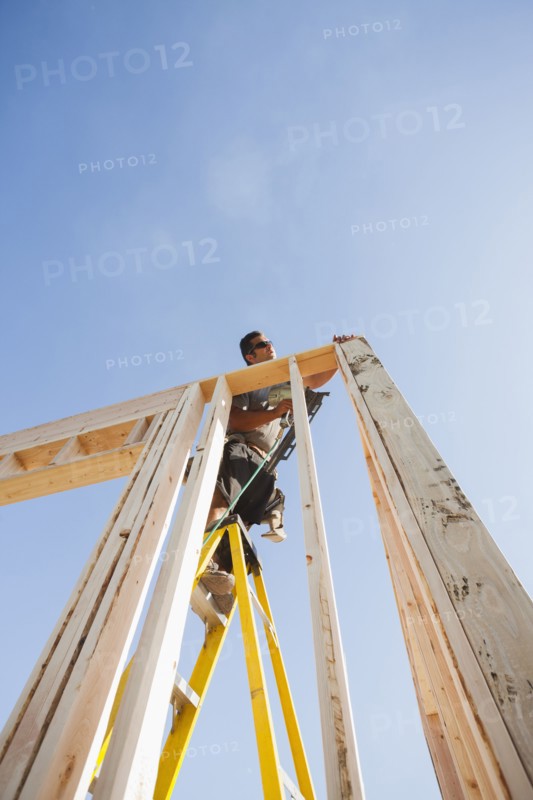 Caucasian man using nail gun on frame