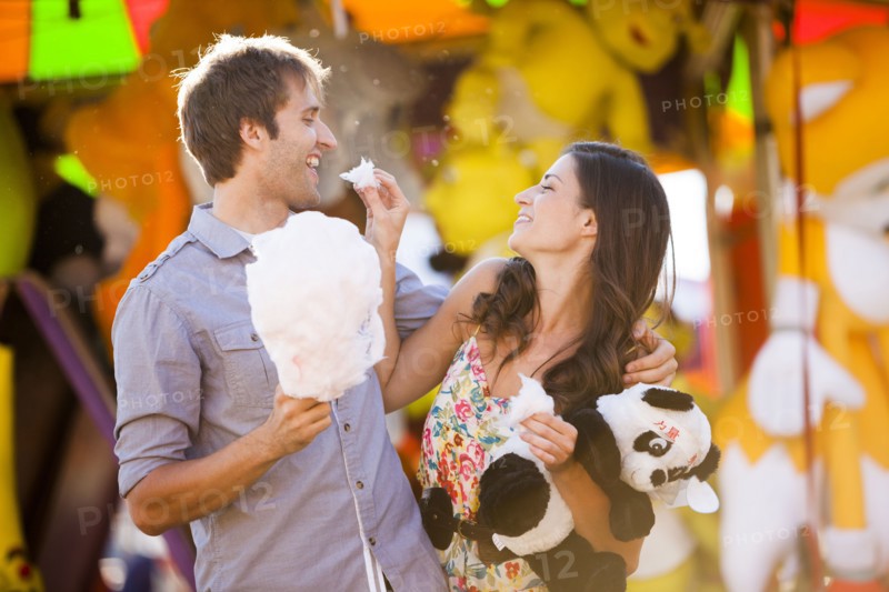 Caucasian couple sharing cotton candy at carnival