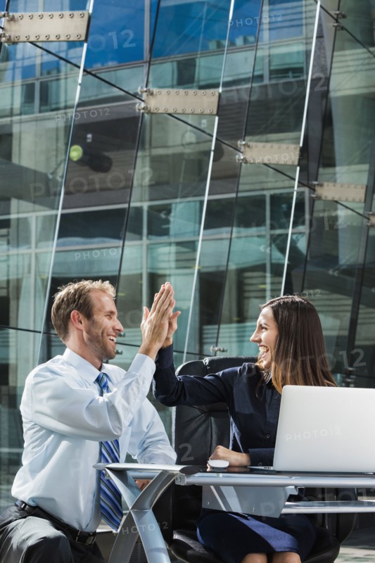 Caucasian business people high fiving at desk