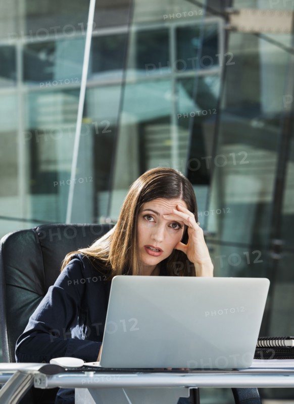 Stressed Caucasian businesswoman at laptop