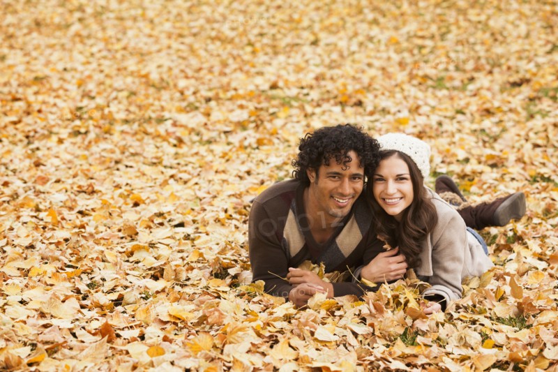 Couple laying in autumn leaves