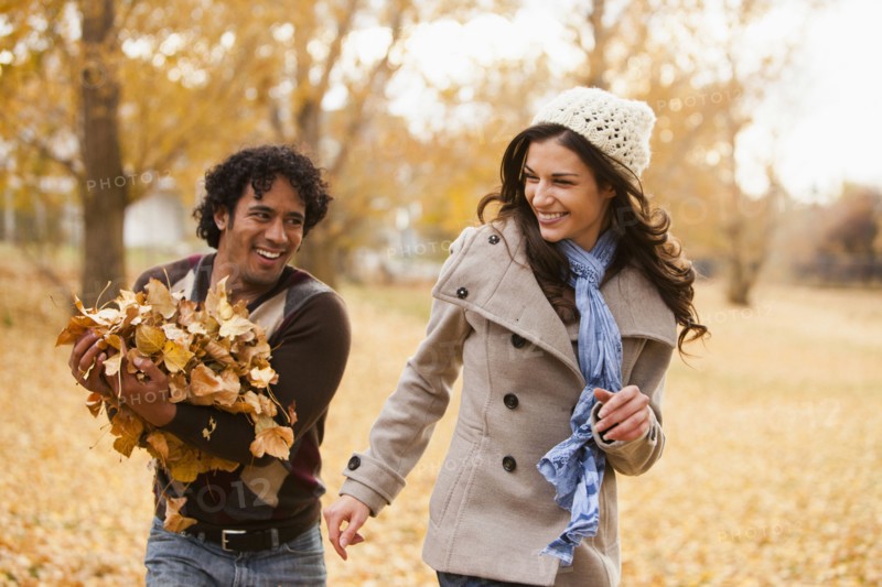 Couple playing in autumn leaves