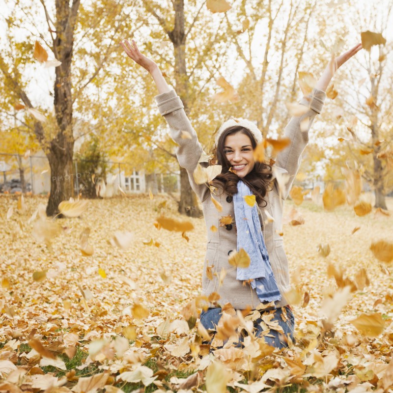 Caucasian woman playing in autumn leaves
