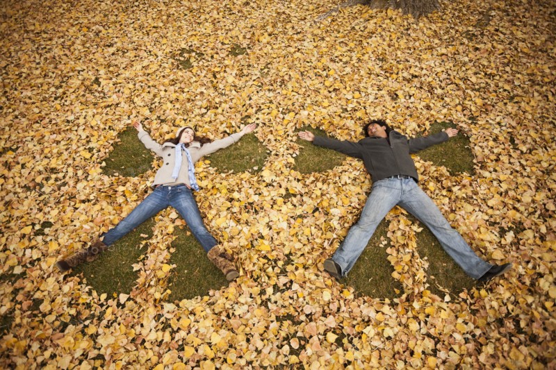 Couple making angel in autumn leaves