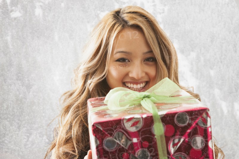 Mixed race woman holding present in snow
