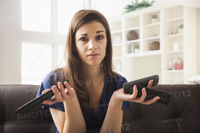 Caucasian woman with multiple remotes on sofa
