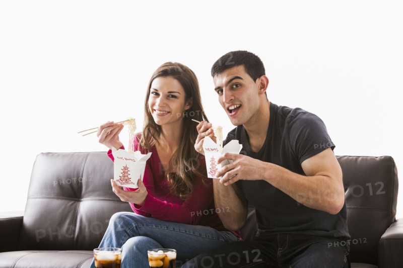 Couple eating Chinese food on sofa