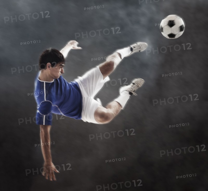 Hispanic soccer player kicking ball in mid air