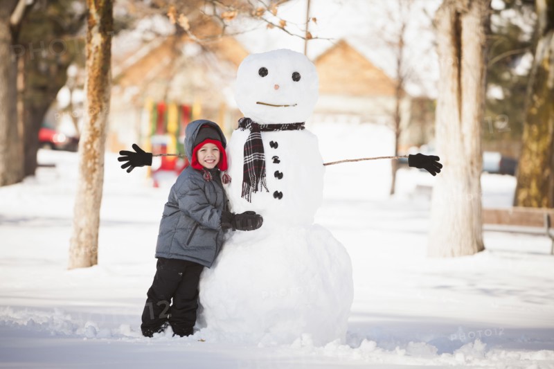 Caucasian boy building snowman in snow