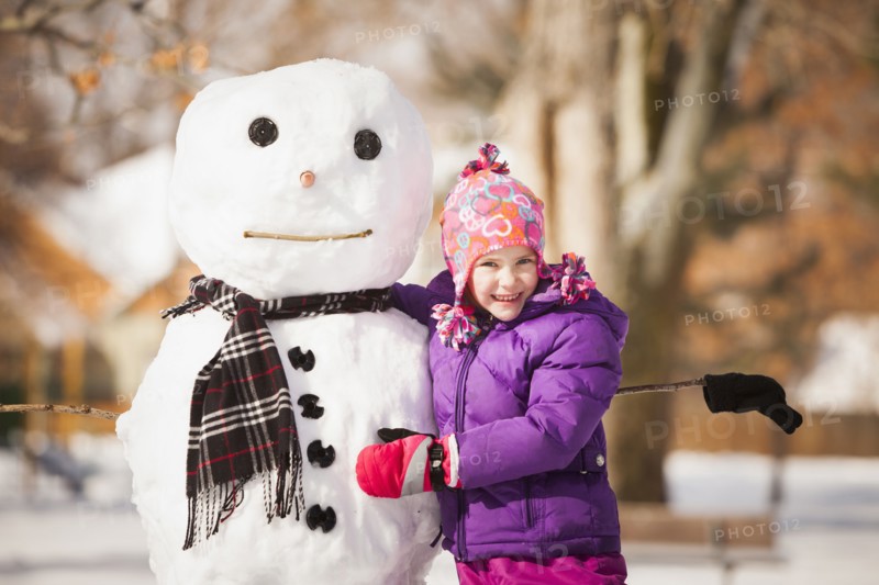 Caucasian girl building snowman in snow