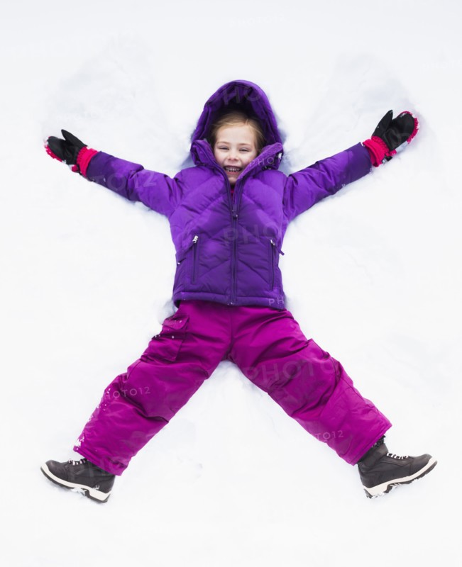 Caucasian girl making snow angel outdoors