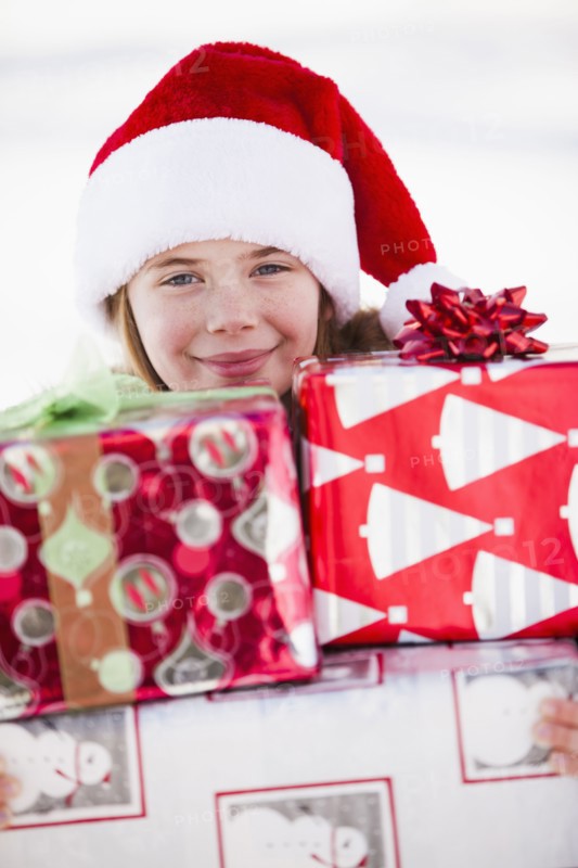 Caucasian boy in Santa hat holding Christmas presents