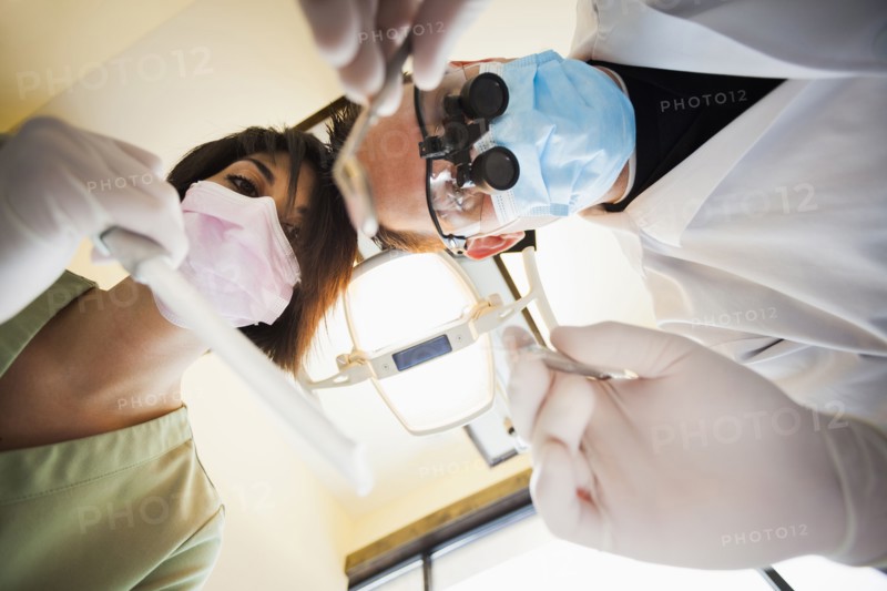 Dentist and nurse towering over patient in office