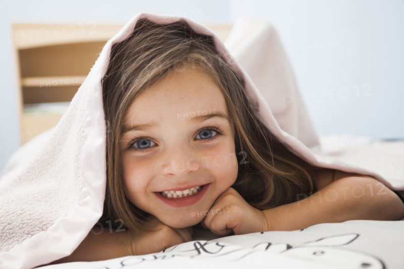 Caucasian girl smiling under covers