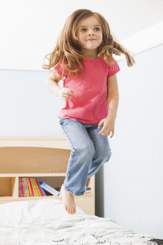 Caucasian girl jumping on bed