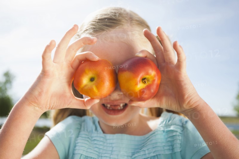 Caucasian girl holding fruit over eyes
