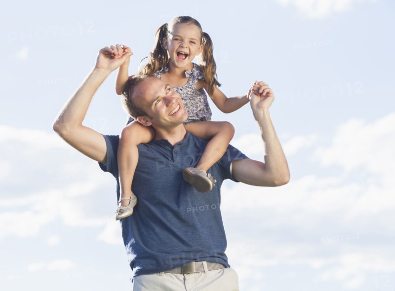 Caucasian father carrying daughter on shoulders