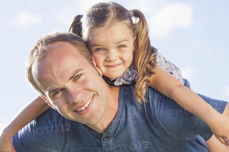 Caucasian father carrying daughter on shoulders