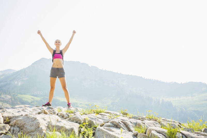 Caucasian woman cheering on rocky hilltop