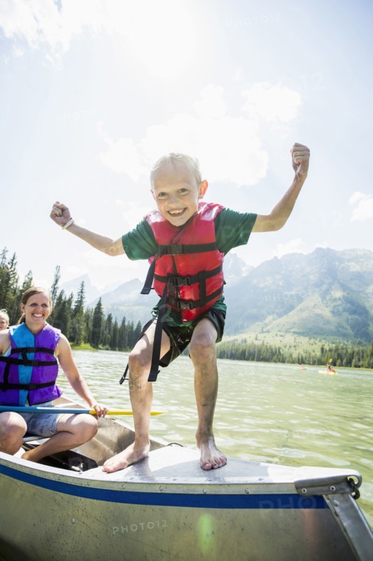 Caucasian boy standing on canoe on lake