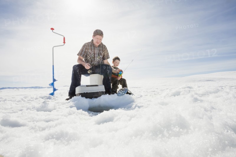 Caucasian father and son ice fishing