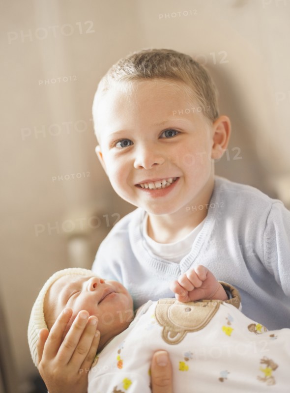 Caucasian boy holding newborn baby brother