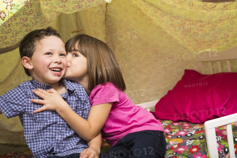 Caucasian children kissing in blanket fort