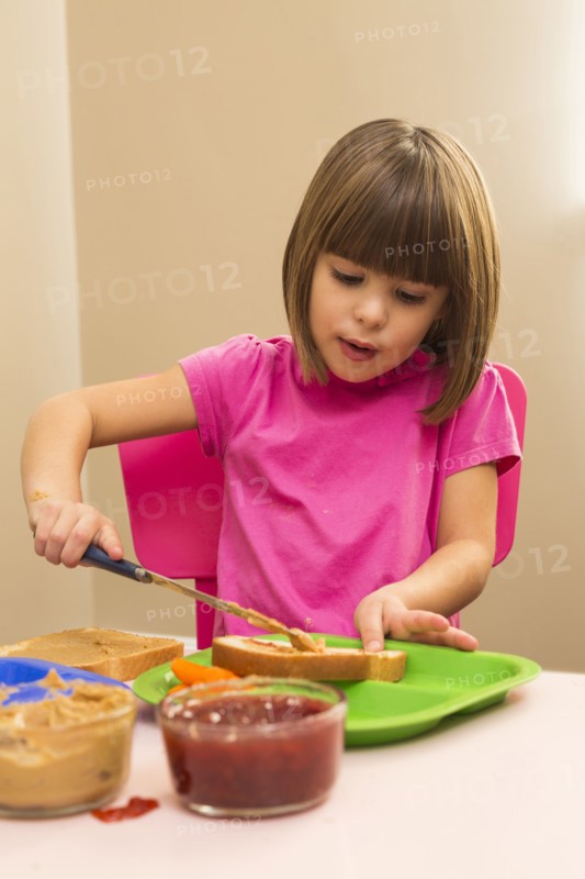 Caucasian girl making sandwich in kitchen