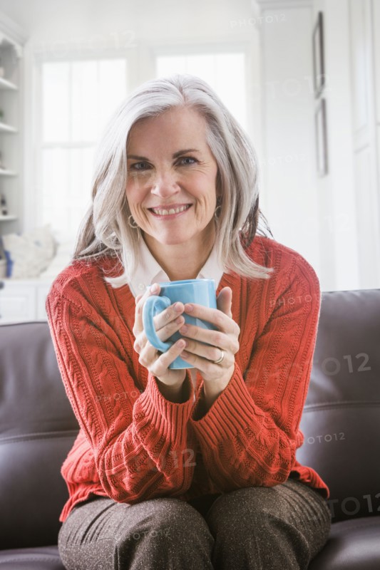 Portrait of Caucasian woman drinking coffee on sofa