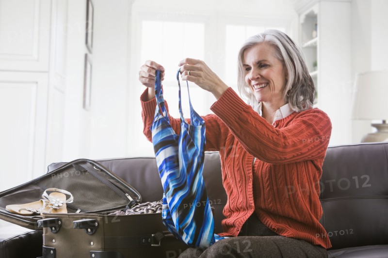 Caucasian woman packing bathing suit in suitcase