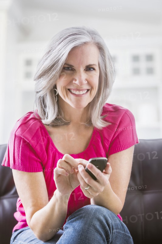 Portrait of smiling Caucasian woman text messaging on sofa