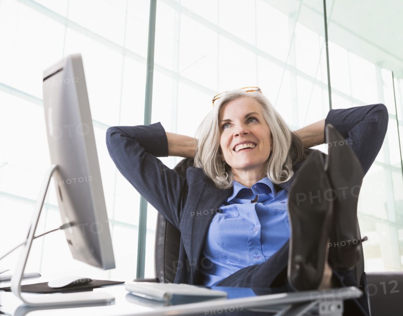 Confident Caucasian businesswoman with feet up on desk