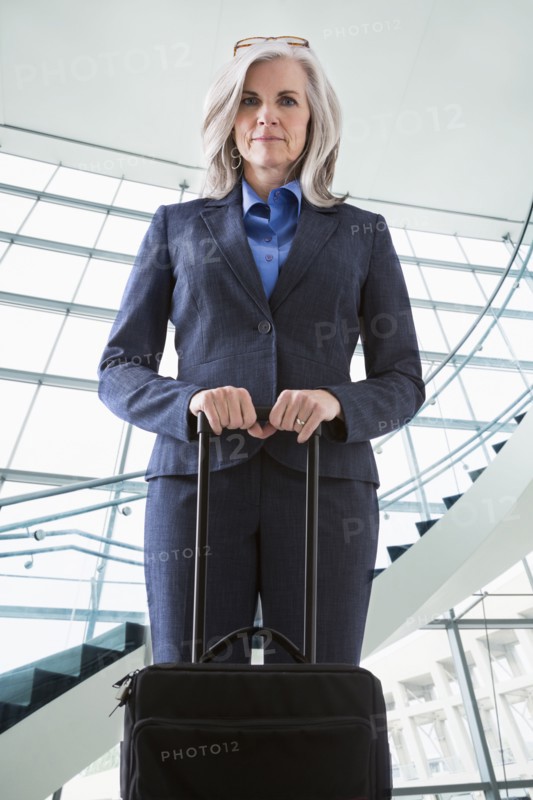 Portrait of confident Caucasian businesswoman with suitcase
