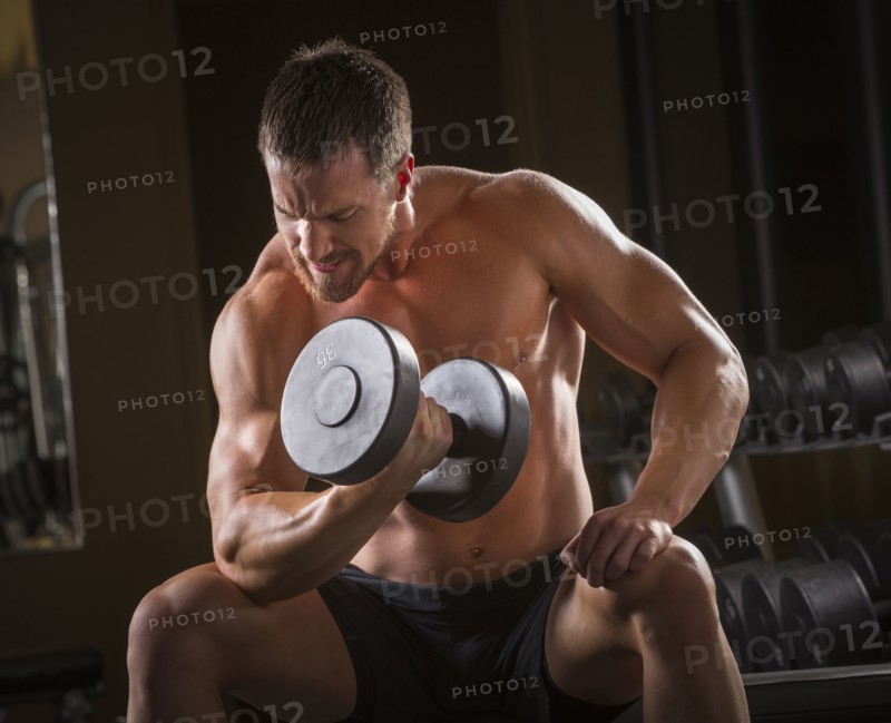 Caucasian man doing biceps curls with dumbbell in gym