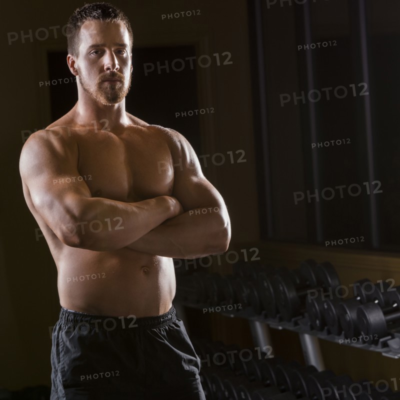 Portrait of confident Caucasian man with bare chest in gym