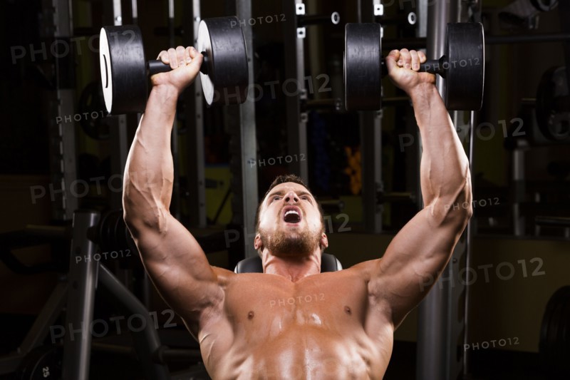 Caucasian man doing incline chest presses with dumbbells in gym