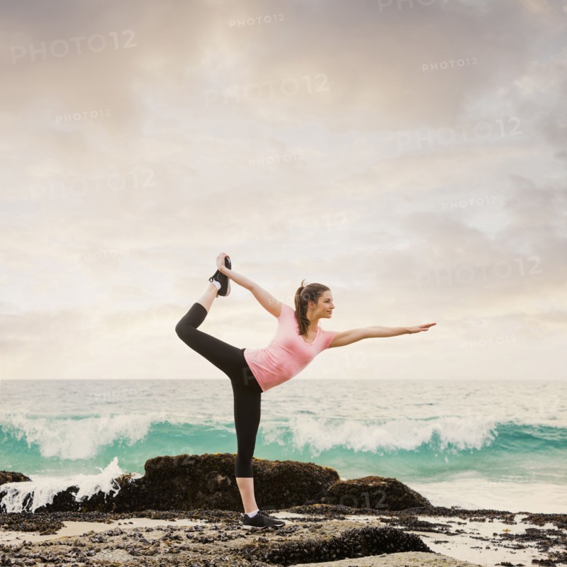 Caucasian woman stretching on beach