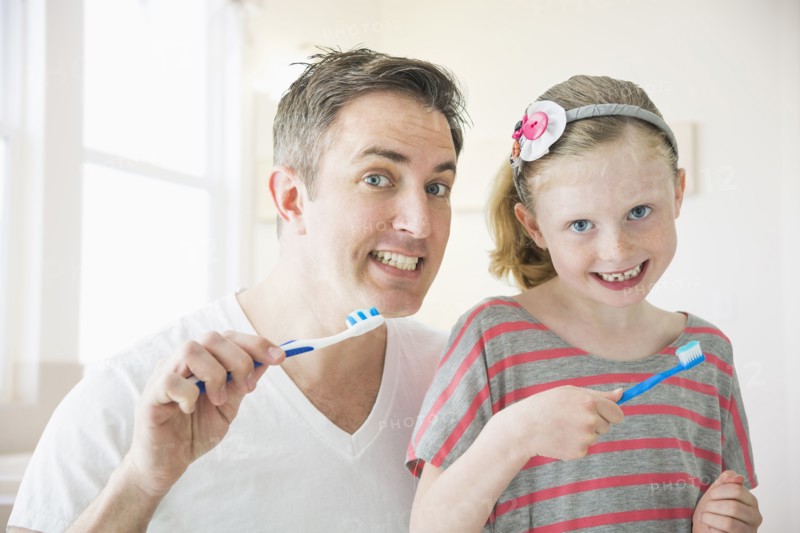 Caucasian father and daughter brushing their teeth