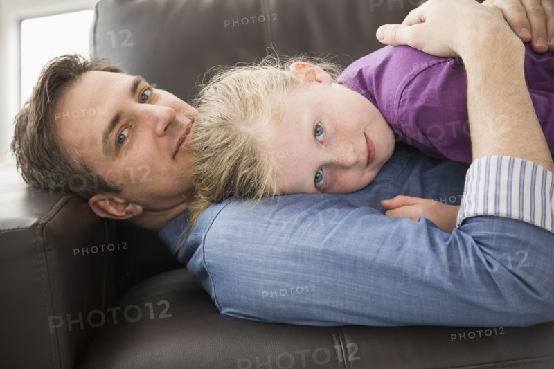 Caucasian father and daughter relaxing on sofa