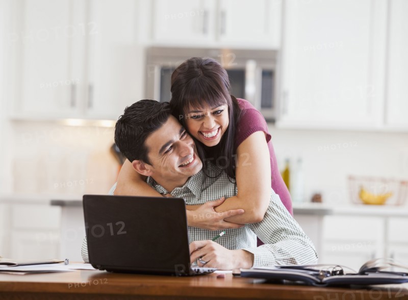 Hispanic couple hugging at laptop