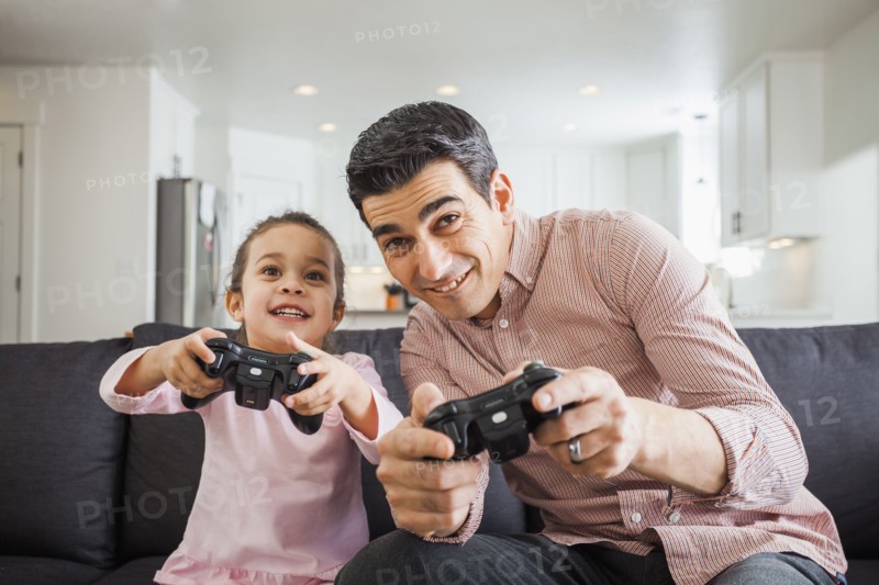 Father and daughter playing video games in living room