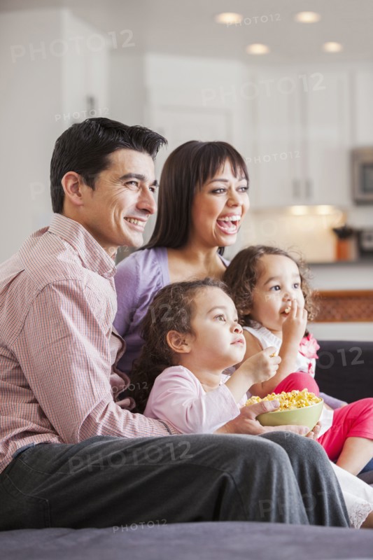 Family watching television together on sofa