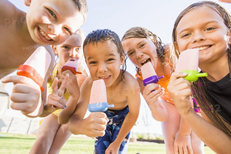 Caucasian children eating popsicles outdoors