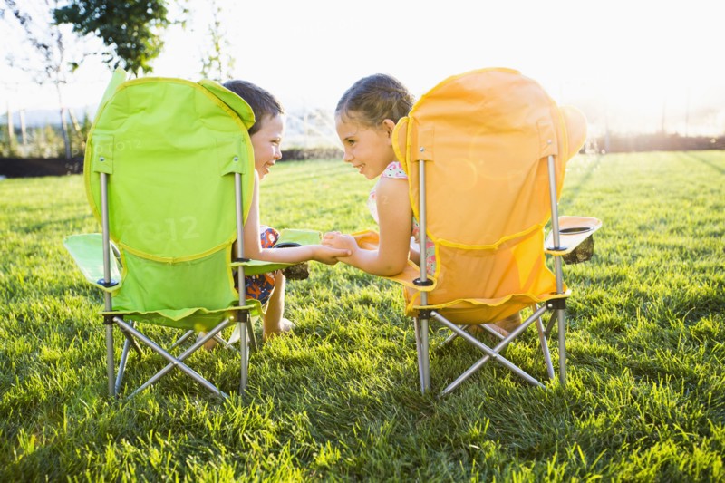Caucasian children relaxing in lawn chairs in backyard