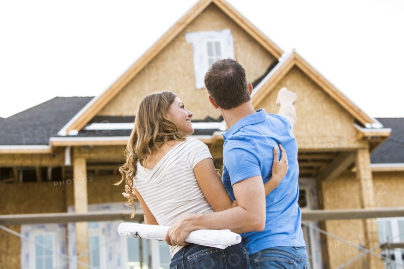 Caucasian couple admiring house under construction