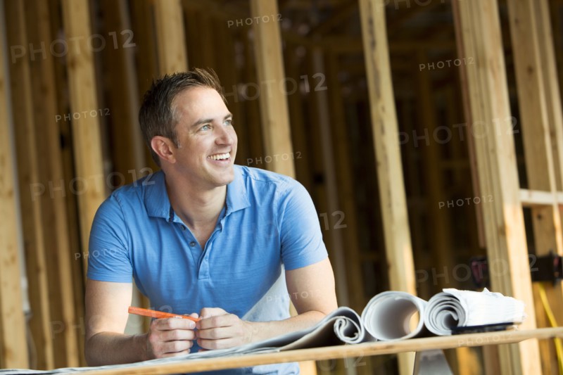 Caucasian man with blueprints in house under construction