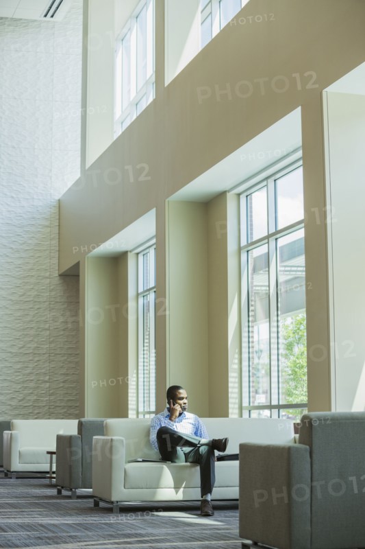 Black businessman talking on cell phone in office lobby