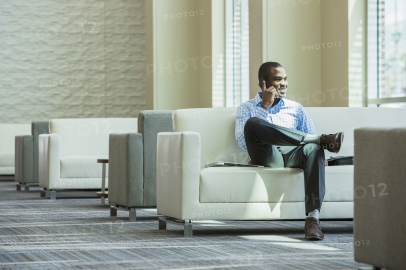 Black businessman talking on cell phone in office lobby