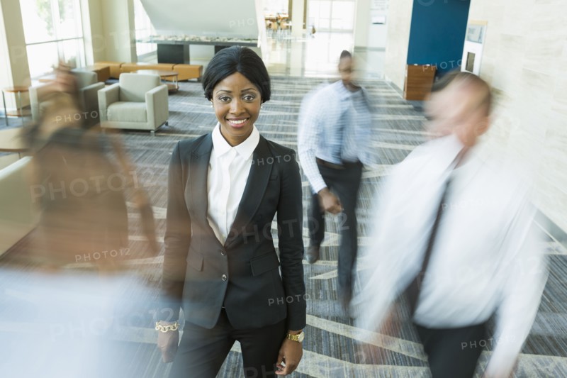 Businesswoman standing still in busy office lobby